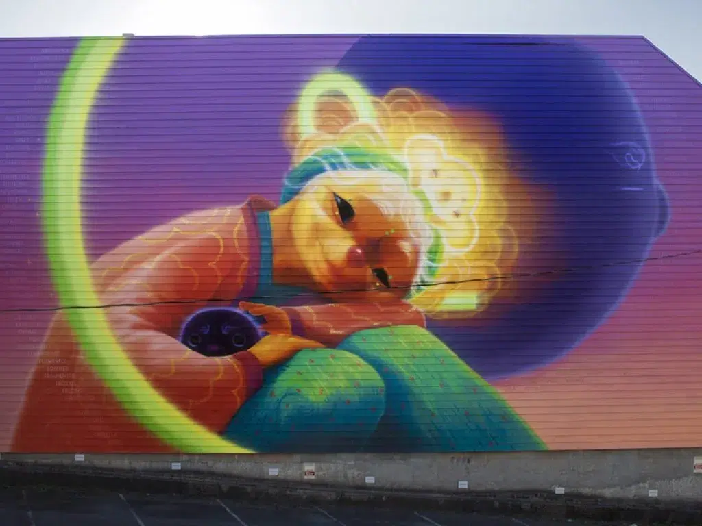 A colorful mural of a girl sitting on a building.
