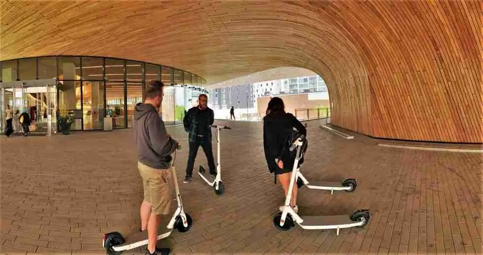 A group of people on scooters in front of a building.