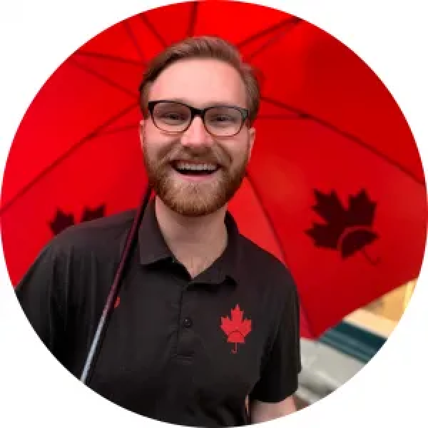 A canadian man holding a red umbrella.