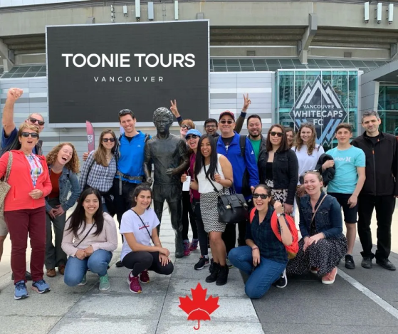 A group of people posing in front of a sign that says tonie tours vancouver.