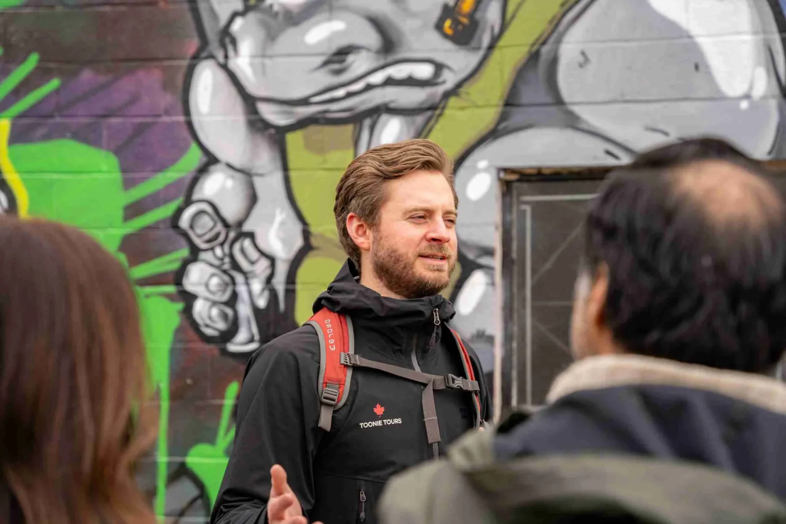 A group of people talking in front of a graffiti wall.