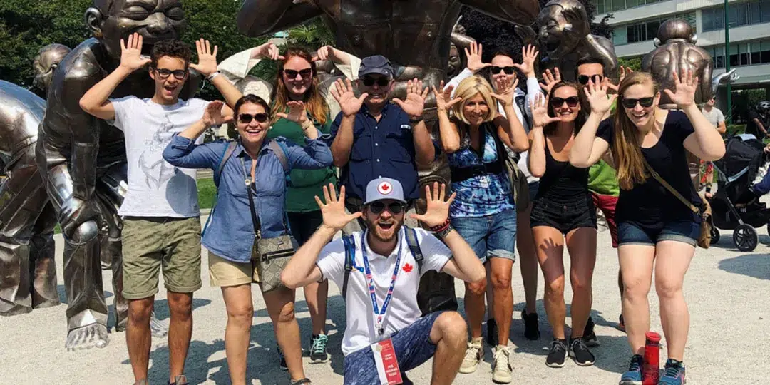 A group of people posing in front of a statue.