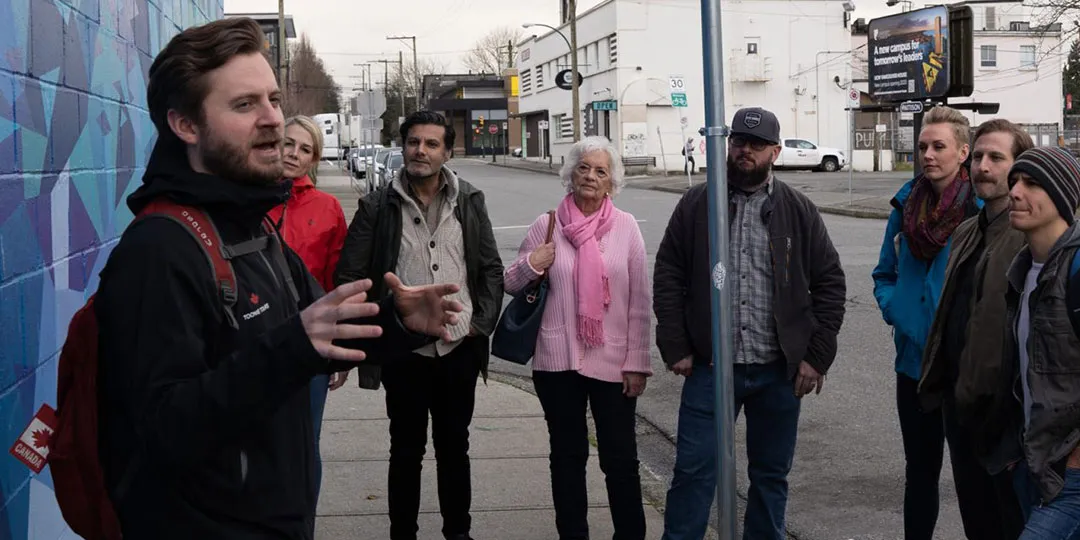 A group of people standing in front of a mural.